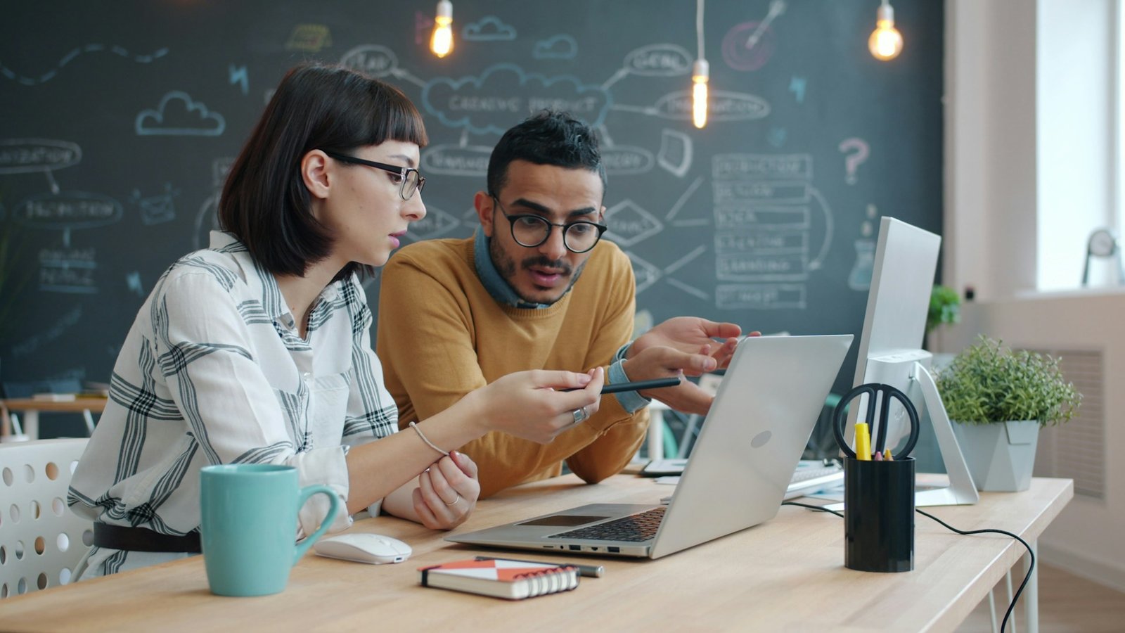 Two colleagues collaborating over a laptop at a desk, planning together